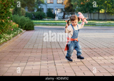 Funny bambina salti di gioia.Un giovane bambino in tuta in jeans Foto Stock