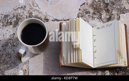 Tazza da caffè e un piccolo taccuino Lista da fare con spazio per mettere il proprio testo,carta bianca Foto Stock
