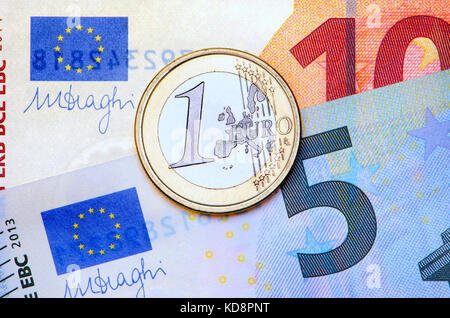 1 moneta da Euro su banconote da 5 e 10 Euro Foto Stock