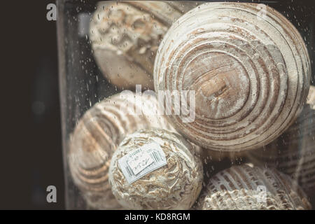 Noirmoutier, Francia - luglio 03, 2017 : nella vetrina di un negozio, sfere di legno scolpito all'interno di un vaso di vetro Foto Stock