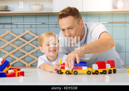 Bella gioiosa padre guardando il toy train Foto Stock