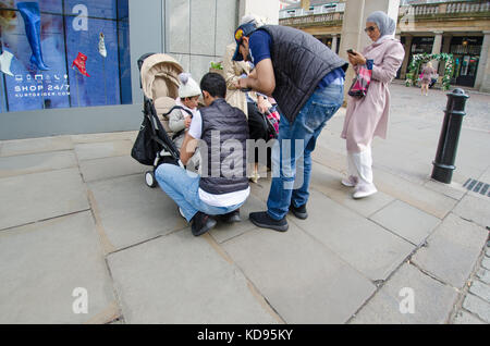 Londra, Inghilterra, Regno Unito. La famiglia musulmana in Covent Garden - gli uomini alla ricerca dopo i bambini Foto Stock