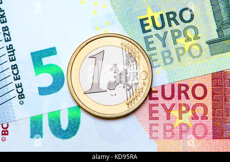 1 moneta da Euro su banconote da 5 e 10 Euro Foto Stock