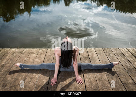 Donna facendo il pieno si divide su un pontile dall'acqua Foto Stock