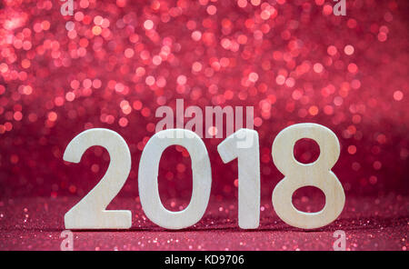 Nuovo anno 2018 bianco numero di legno su carta rossa con luci glitter Foto Stock