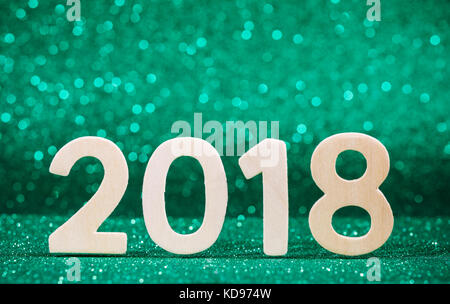 Nuovo anno 2018 bianco numero di legno su carta verde glitter con luci Foto Stock