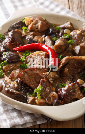 Stufati di carne di vitello con bosco selvatico funghi in salsa di vino in un recipiente verticale. Foto Stock