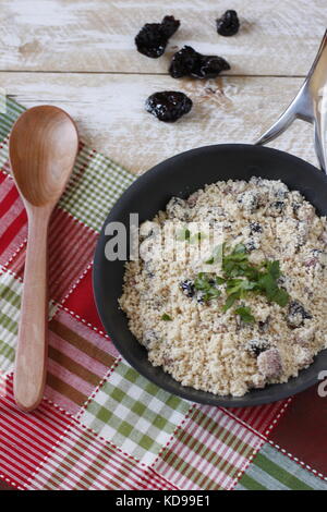 Piatto brasiliano farofa, con pancetta e prugne all'interno della padella su tovagliolo rosso e verde Foto Stock