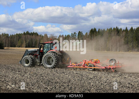 SALO, FINLANDIA - 7 MAGGIO 2017: L'agricoltore coltiva il campo con il trattore Valtra rosso e il coltivatore a letto di semina Potila in un bellissimo giorno di primavera. Foto Stock