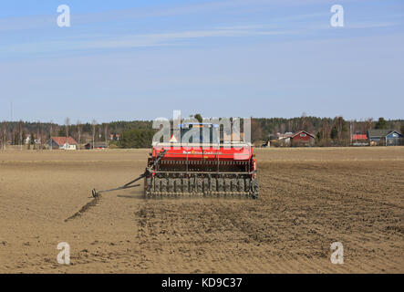 SALO, FINLANDIA - 14 MAGGIO 2017: Trattore agricolo e seminatrice che lavorano sul campo in una giornata di sole primaverile, vista posteriore. Foto Stock