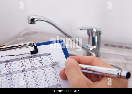 La scrittura a mano con la penna sul consumo di acqua Livello nella parte anteriore del Watertap Foto Stock