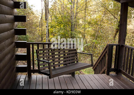 Un'altalena in legno artigianale è appesa al portico anteriore di una rustica capanna in legno nel Wisconsin occidentale. Foto Stock