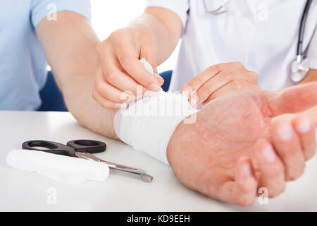 Close-up di medico donna del bendaggio al polso del paziente Foto Stock