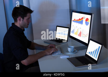 Giovane uomo che lavora al computer in ufficio di notte Foto Stock