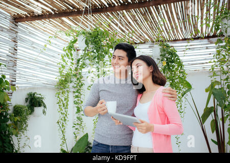 Amore giovane a casa. giovani asiatici rilassante su un balcone sul giardino. Foto Stock