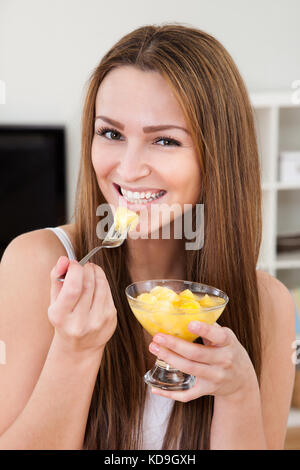 Primo piano di un affascinante giovane donna di mangiare insalata di frutta Foto Stock