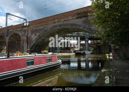 Un narrowboat e Vittoriano ponti ferroviari a Castlefield Conca al Bridgewater Canal, Manchester, Inghilterra, Regno Unito Foto Stock