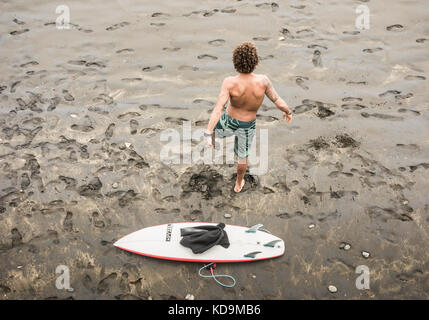 Surfista che si allunga sulla spiaggia. Foto Stock