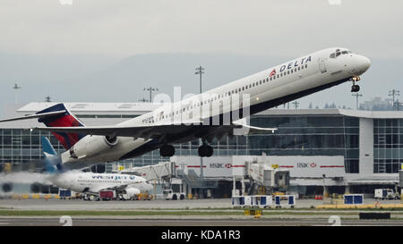 Richmond, Columbia Britannica, Canada. 6 ottobre 2017. Un aereo di linea regionale Delta Air Lines McDonnell Douglas MD-90 (N923DN) a cassone stretto a corsia singola decolla dall'aeroporto internazionale di Vancouver. Sullo sfondo: Un Boeing 737 di Westjet Airlines attraccato in uno dei cancelli di arrivo/partenza dell'aeroporto. Crediti: Bayne Stanley/ZUMA Wire/Alamy Live News Foto Stock