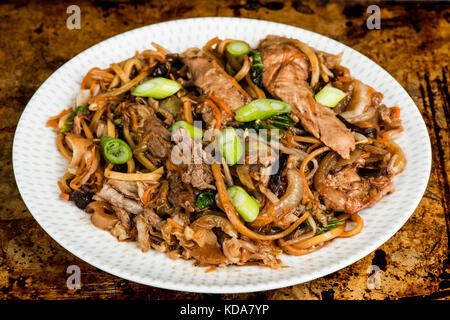 Stile cinese anatra hoisin tagliatelle con pak choi contro un distressed bruciato forno o la griglia da forno Foto Stock