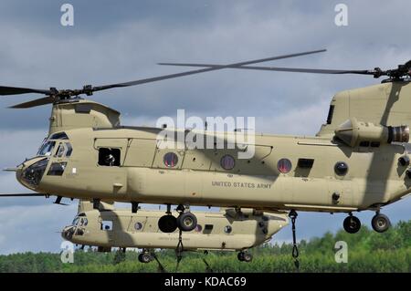 I soldati statunitensi e polacchi utilizzano gli elicotteri CH-47 Chinook dell'esercito statunitense per caricare le armi di artiglieria Howitzer M777 nell'area di addestramento Bemowo Piskie durante l'esercitazione Saber Strike il 7 giugno 2017 a Bemowo Piskie, Polonia. Foto Stock