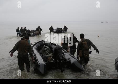 I soldati del corpo dei Marines degli Stati Uniti e i loro familiari trainano barche zodiacali in mare durante il Jane Wayne Day presso la base dei Marines Camp Lejeune il 19 ottobre 2013 a Jacksonville, Carolina del Nord. Gli eventi del Jane Wayne Day consentono ai partecipanti di sperimentare in prima persona gli scenari di addestramento della Marina. Foto Stock