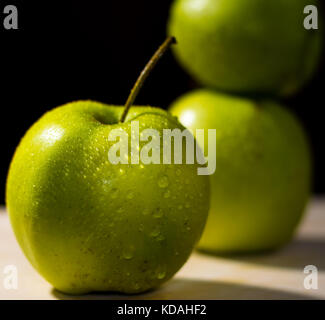 Tre mele verdi, focus sul colore di primo piano e sfondo scuro Foto Stock