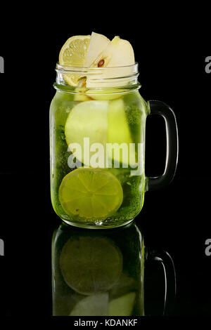 Cocktail con limone, apple e pistacchi sciroppo in vaso su sfondo nero con la riflessione Foto Stock