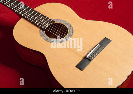 Chitarra acustica sul velluto rosso tessuto, closeup oggetto Foto Stock