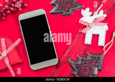 Smart phone e decorazione di Natale su sfondo rosso. Foto Stock
