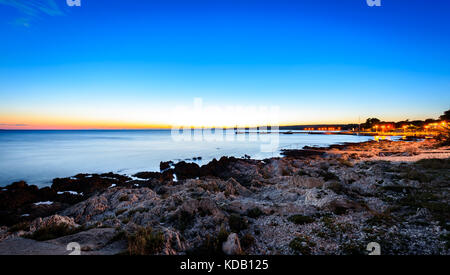 La sera al tramonto foto orizzontale della porta marina di Selve Croazia. lunga esposizione foto del tramonto, rocce sulla riva e mare calmo con il villaggio di pescatori di Foto Stock