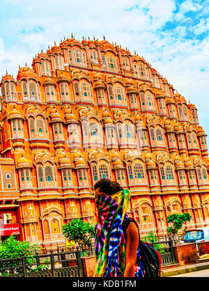 Una giovane donna indiana in Colorati luminosamente sari, camminando di fronte al palazzo dei venti a Jaipur, India Foto Stock