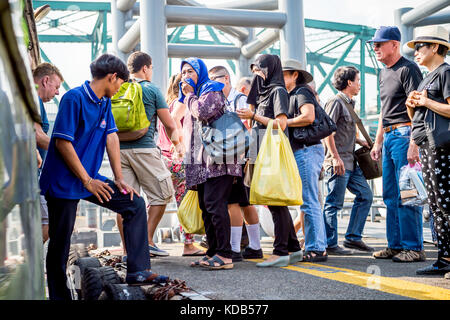 Turisti e locale thailandese persone il pendolarismo sbarcare e a bordo del traghetto che corre il fiume Chao Phraya a Bangkok in Tailandia. Foto Stock