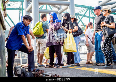 Turisti e locale thailandese persone il pendolarismo sbarcare e a bordo del traghetto che corre il fiume Chao Phraya a Bangkok in Tailandia. Foto Stock