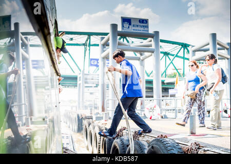 Turisti e locale thailandese persone il pendolarismo sbarcare e a bordo del traghetto che corre il fiume Chao Phraya a Bangkok in Tailandia. Foto Stock