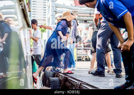 Turisti e locale thailandese persone il pendolarismo sbarcare e a bordo del traghetto che corre il fiume Chao Phraya a Bangkok in Tailandia. Foto Stock