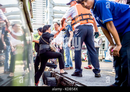 Turisti e locale thailandese persone il pendolarismo sbarcare e a bordo del traghetto che corre il fiume Chao Phraya a Bangkok in Tailandia. Foto Stock