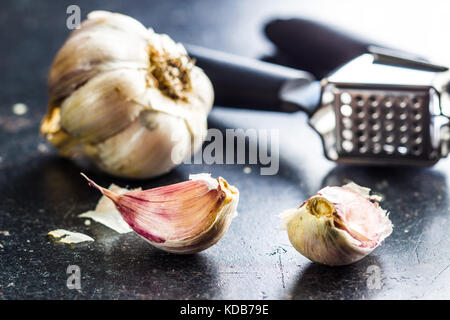 Aglio fresco e aglio pressore al tavolo della cucina. Foto Stock