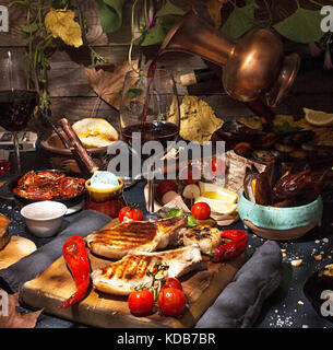 Overhead del tavolo per la cena. Assortiti barbecue grigliate di carne e pesce con verdure. Vitigno di colata da jar. La carne di maiale bistecche ai ferri, salmone trota, cozze Foto Stock