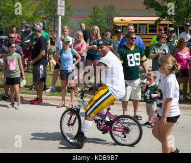 Green Bay, WI - 1 agosto 2017: green bay packer phillips kalif cavalca un giovane fan bike dopo la pratica di gioco del calcio. la comunità di proprietà team ha una lunga Foto Stock