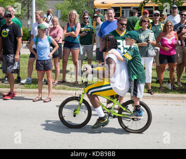 Green Bay, WI - 1 agosto 2017: Aaron Jones cavalca un giovane fan bike dopo la pratica di gioco del calcio. la comunità di proprietà Green Bay Packers hanno una lunga tradi Foto Stock