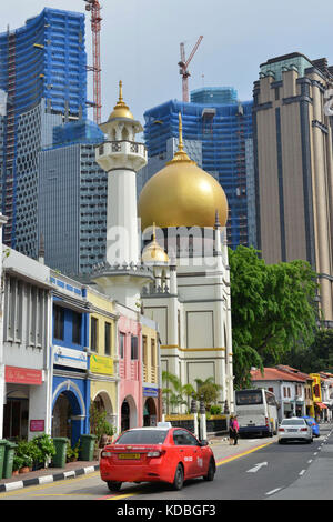 Singapore. Red taxi di fronte alla Masjid Sultan moschea, Muscat street, quartiere di Rochor. In background, numerosi grattacieli di uffici sotto cons Foto Stock