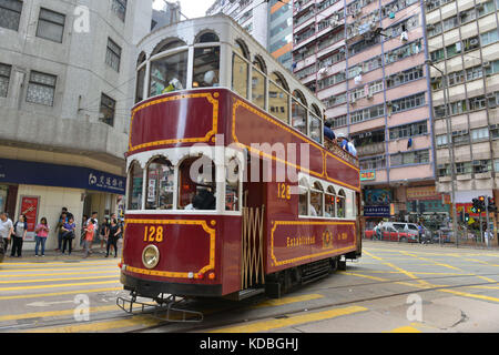 Nella parte inferiore degli edifici, colorato double-decker tram appartenenti ad Hong Kong Tramways con grandi annunci su suoi lati. Vecchio modello rinnovato e vernice Foto Stock