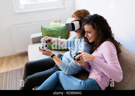 Felice coppia giovane per giocare con i videogiochi con la realtà virtuale auricolari Foto Stock