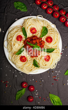 Piastra del delizioso spaghetti bolognese o bolognese con gustosa carne macinata e salsa di pomodoro guarnita con parmigiano e basilico, vista dall'alto Foto Stock