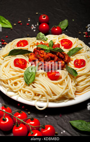 Vista dettagliata del delizioso spaghetti bolognese o bolognese con gustosa carne macinata e salsa di pomodoro guarnita con parmigiano e basilico Foto Stock