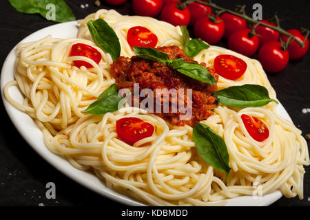 Vista dettagliata del delizioso spaghetti bolognese o bolognese con gustosa carne macinata e salsa di pomodoro guarnita con parmigiano e basilico Foto Stock