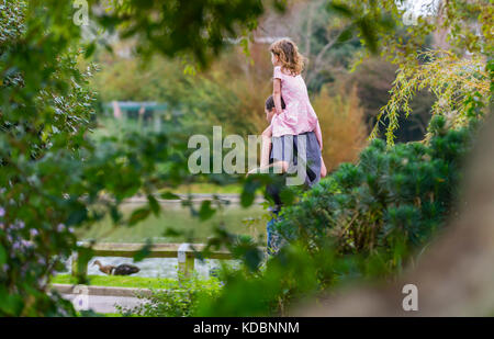 Giovane ragazza viene trasportato su un uomo di spalle, una piggy back ride, attraverso un parco nel Regno Unito. Foto Stock