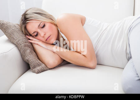 Ritratto di donna con mal di stomaco divano Foto Stock