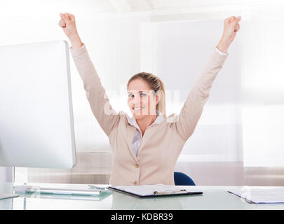 Felice imprenditrice alzando la mano in ufficio Foto Stock